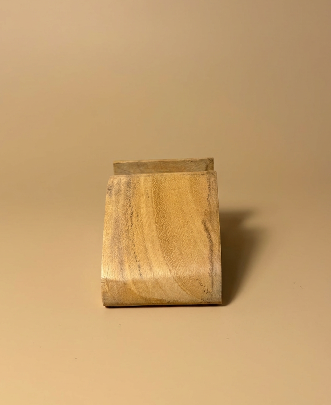 A minimalist wooden phone stand designed for stable, hands-free viewing with a natural, modern aesthetic.
