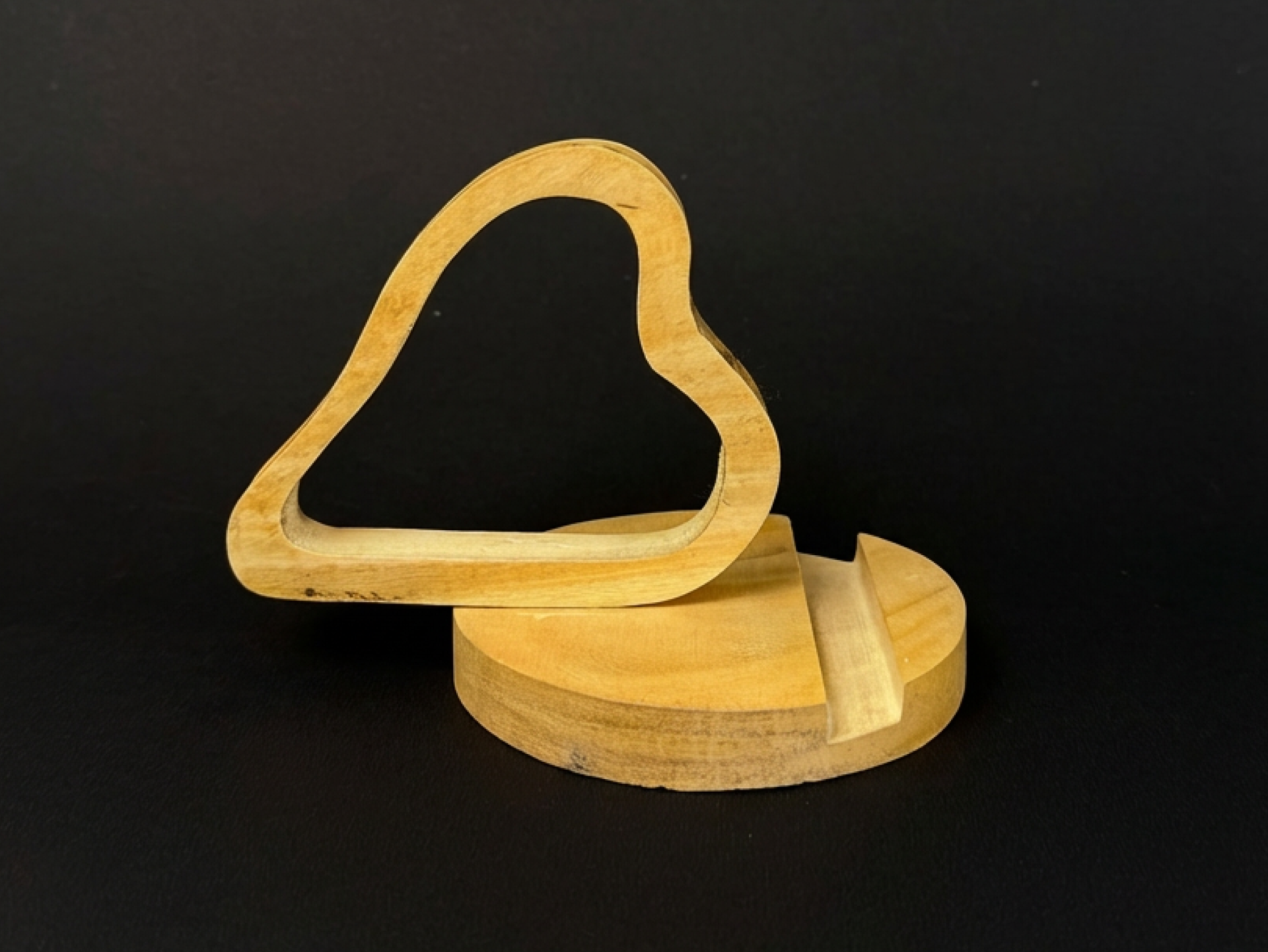 Handcrafted wooden heart-shaped phone stand holding a smartphone on a natural wooden base