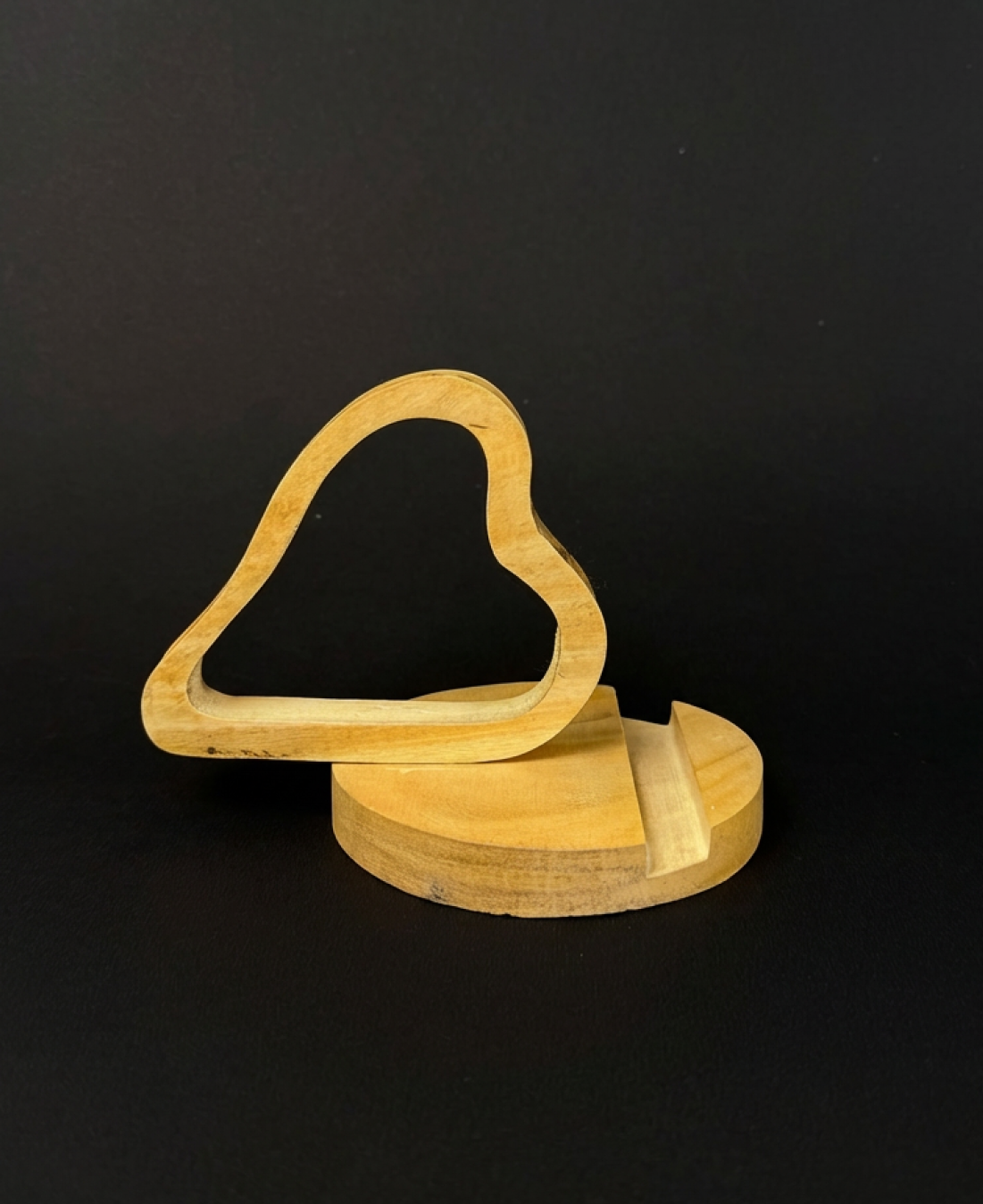 Handcrafted wooden heart-shaped phone stand holding a smartphone on a natural wooden base