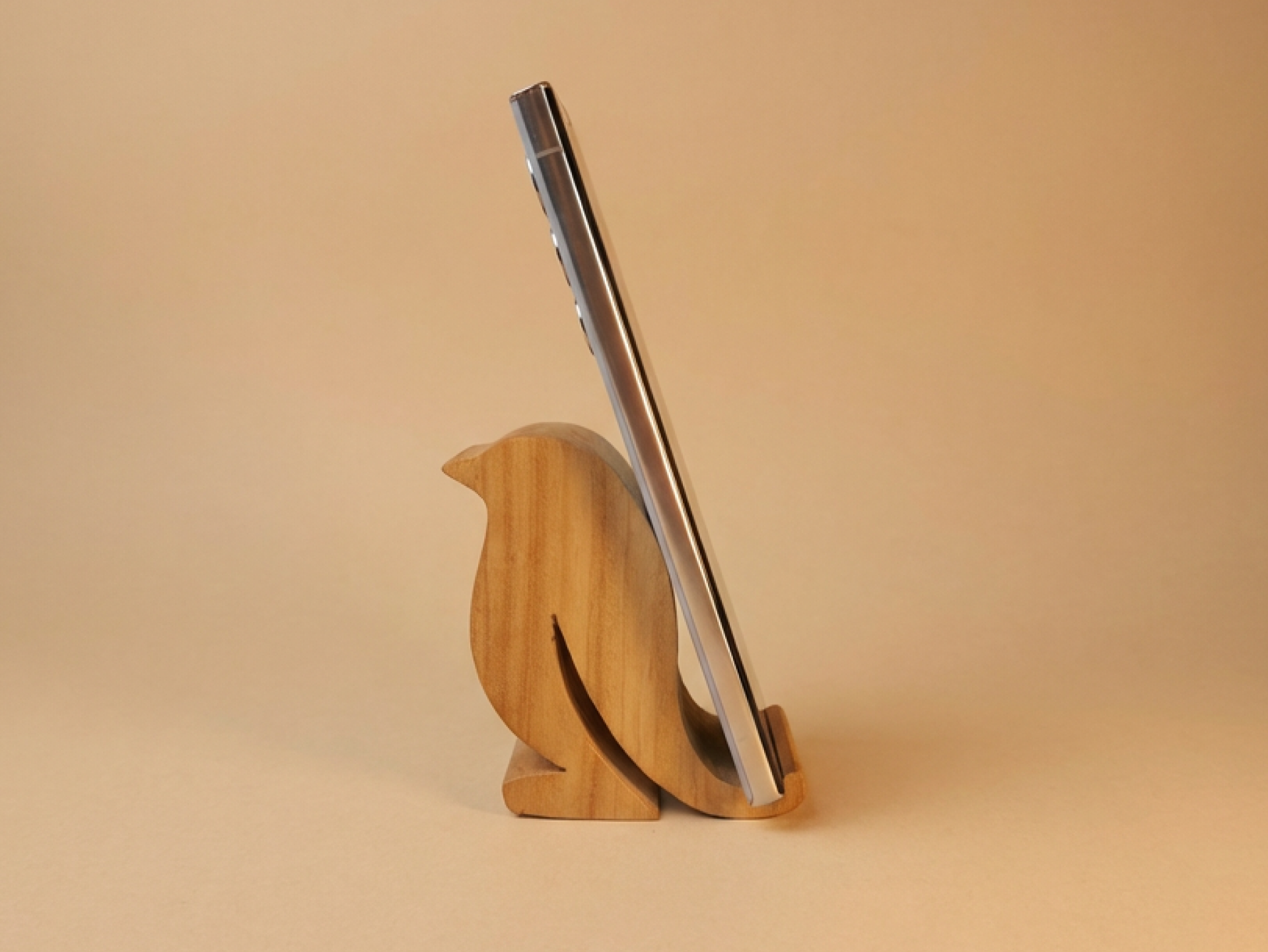 A handcrafted wooden bird-shaped phone stand that blends functionality with minimalist decor.